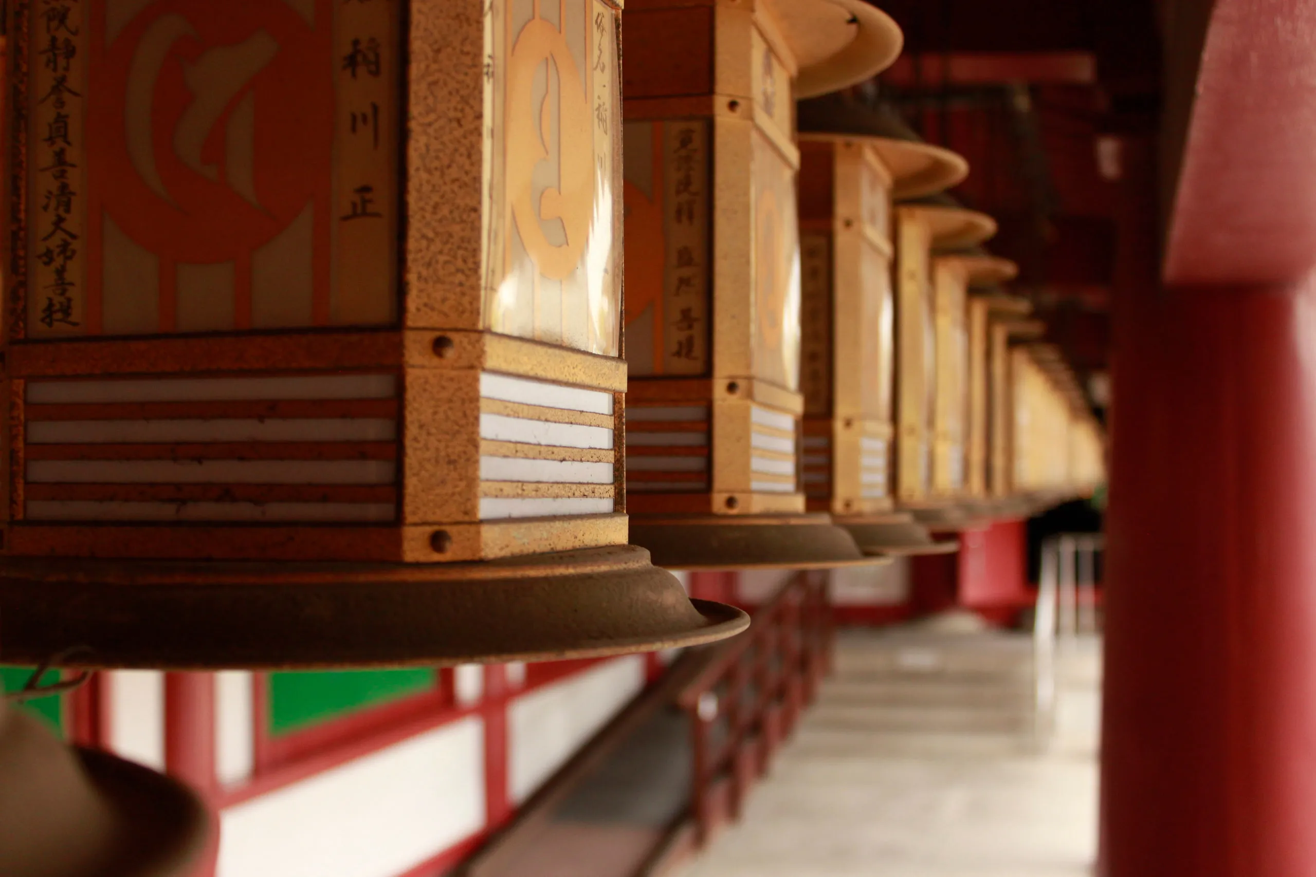 A shallow-focus row of painted lanterns lines a red-pillared corridor.